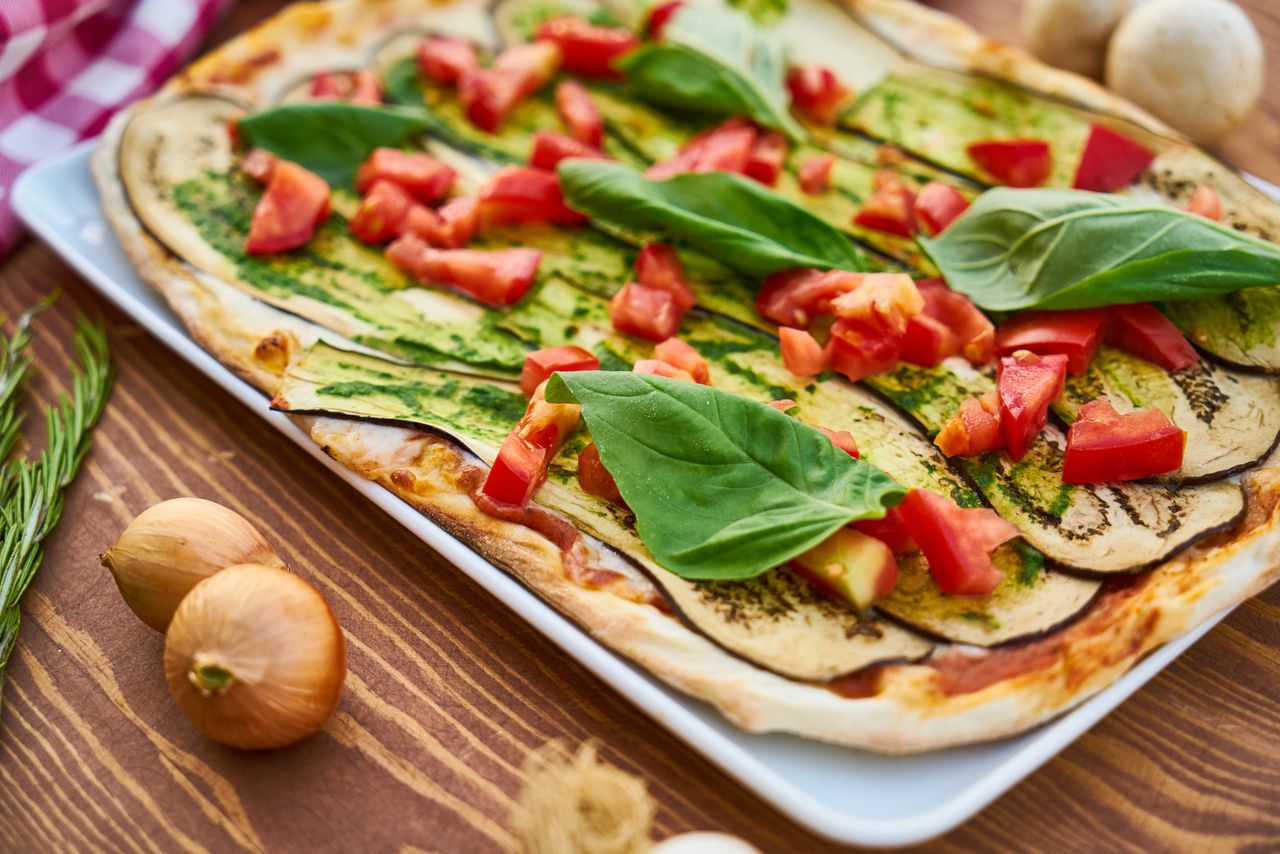 Delicious vegetable pizza featuring fresh eggplant, basil, and tomatoes for a healthy meal.